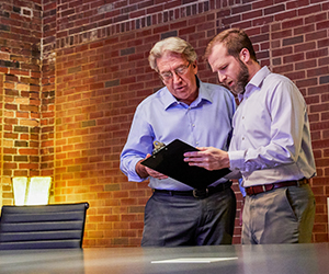 Two men discussing items on clip board.