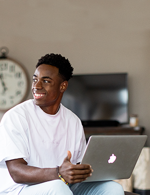 A man at desk with his laptop looking away.
