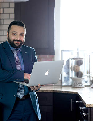 Busey Associate Anish Mehta smiling while holding a laptop
