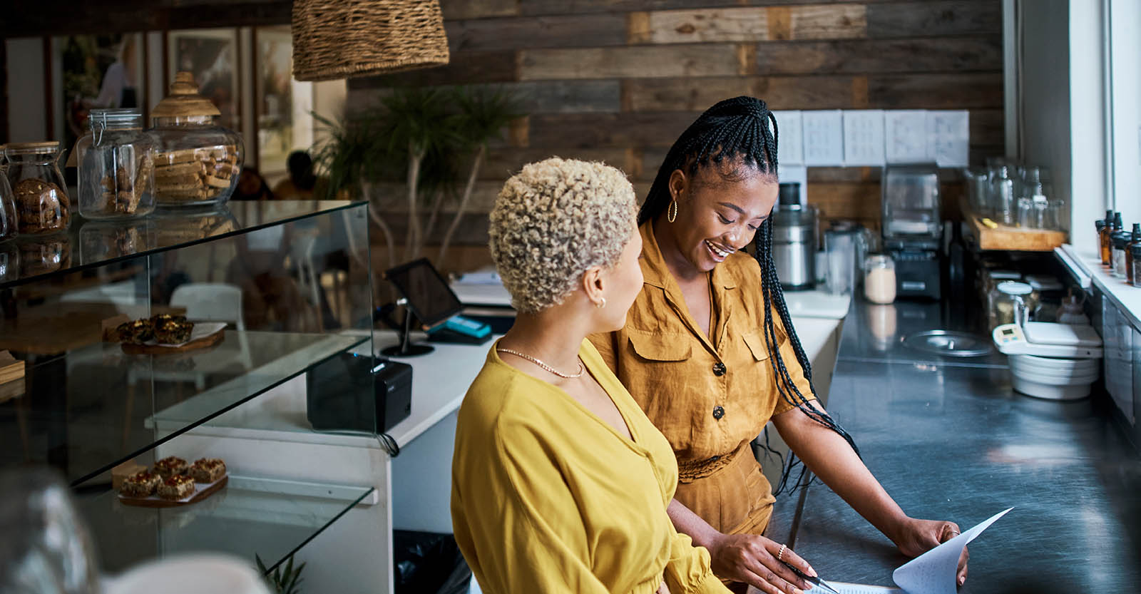 Two women talking to each other while looking down at table.