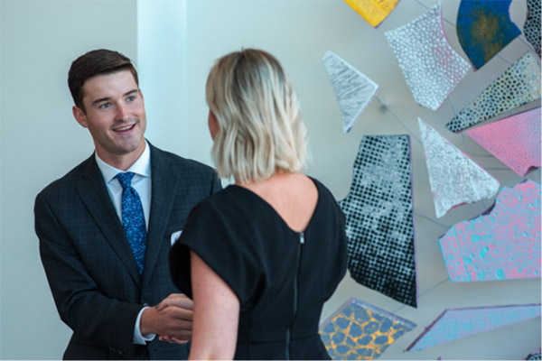 A young man talking to a women in a lobby.