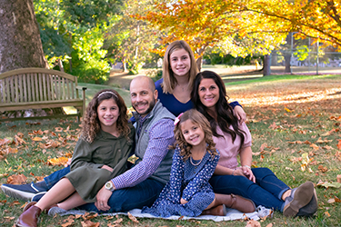 Busey Associate Dan McCarthy with family posing in a park during Autumn.