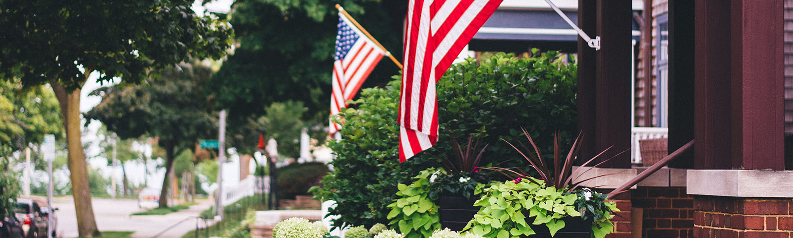 American flags hanging off front porches along a sidewalk