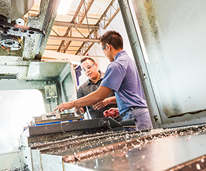 Two men with safety glasses in a metal workshop