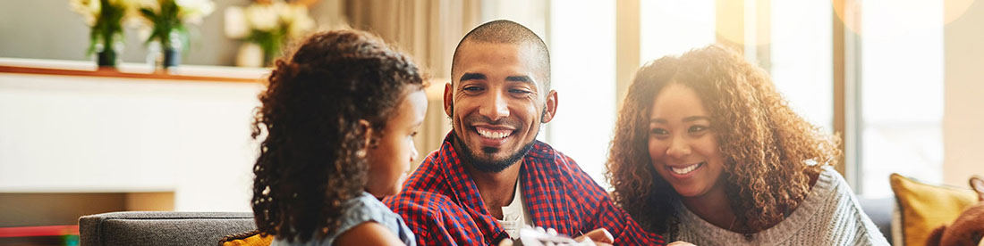 a family of three smiling and looking at each other