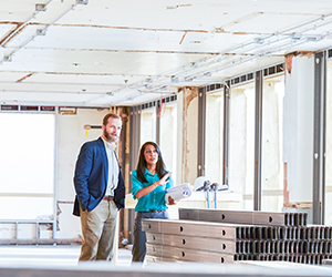 Two people looking toward an open floor in construction.