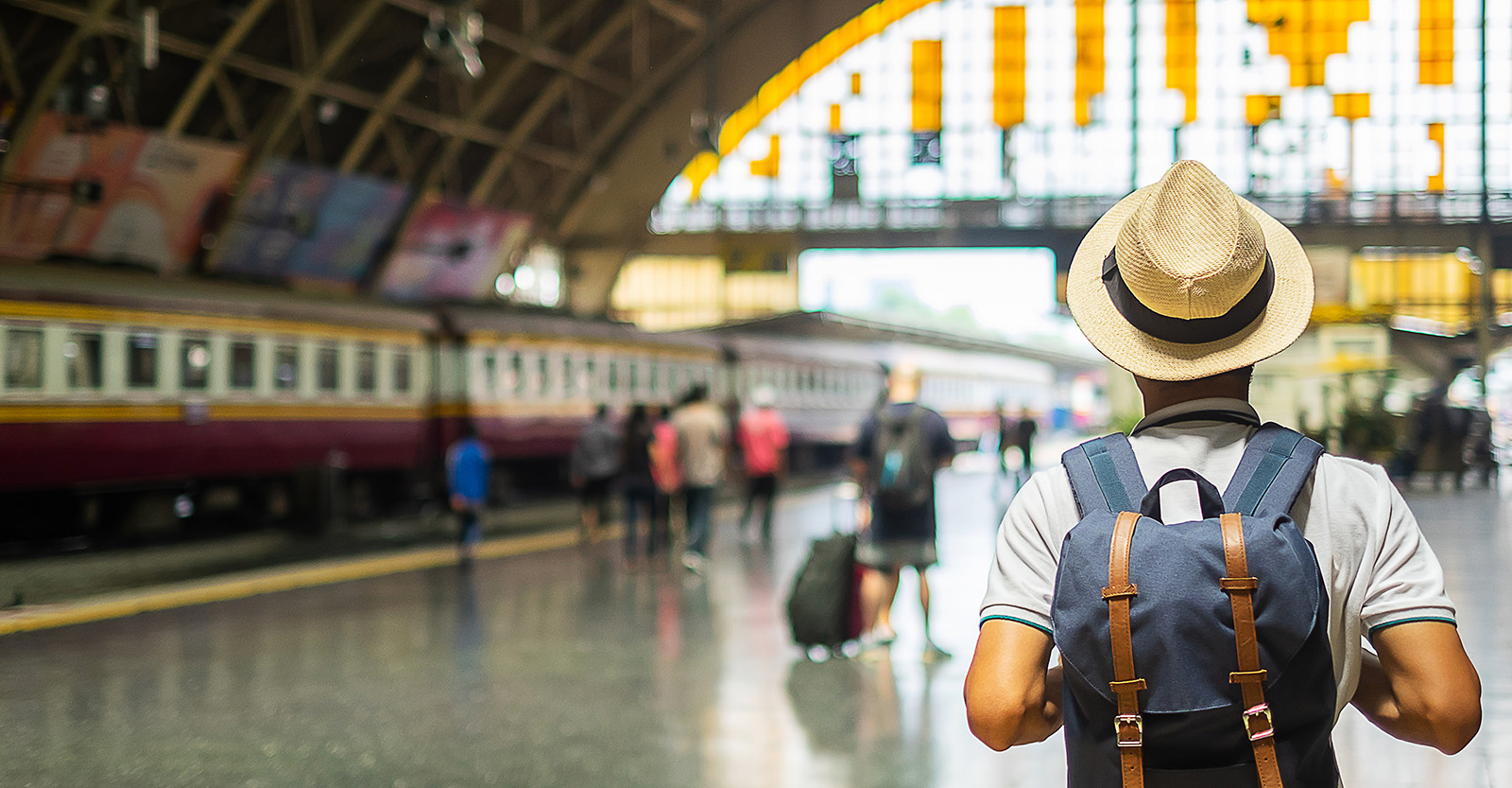a person with a hat and walking with back pack in a train station